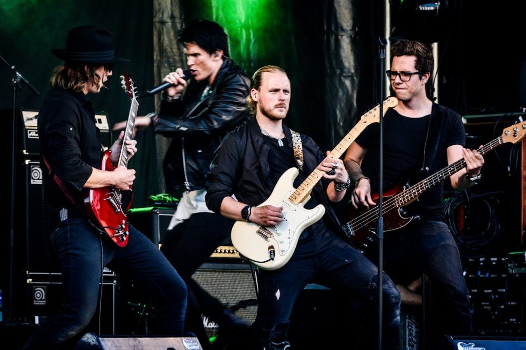 Rock band performing live with guitars and microphone on stage. Energetic and dynamic concert vibe.